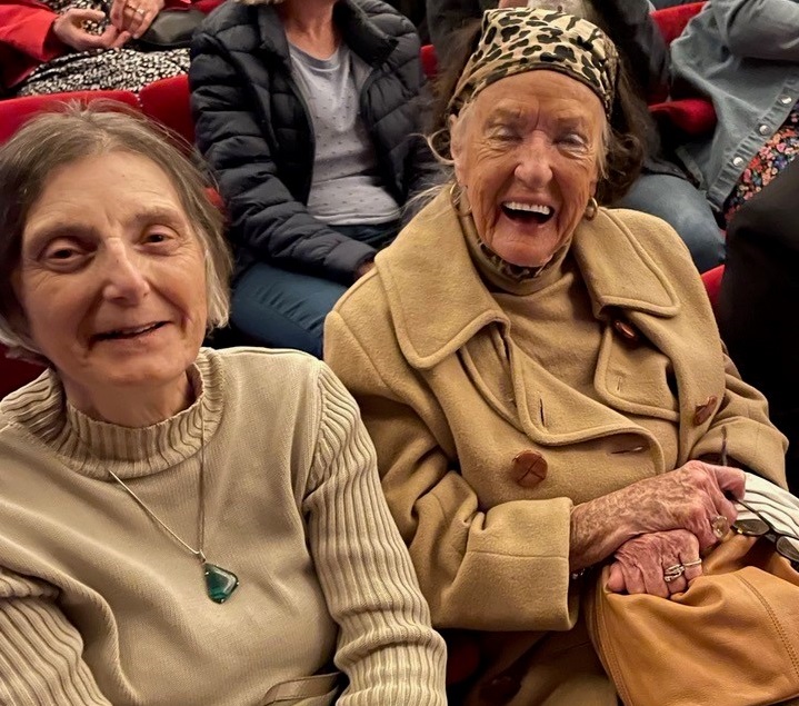 Two ladies sitting in the theatre and laughing